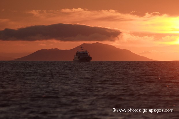 Couché de soleil avec un bareau de croisière et  l'île de Pinzon en arrère plan - Galapagos